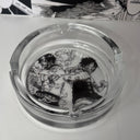 The Ace Luffy Ashtray by SpicedAnime is a clear glass ashtray decorated inside with black-and-white manga-style art of two muscular characters, one wreathed in smoke—a bold anime-themed collectible.