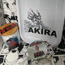 The SpicedAnime Akira Grinder, Jar, Rolling Tray Set features a metal herb grinder, a tray with a robotic hand design, and a glass jar with characters, all displayed on black-and-white manga panels.