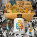 The Simpsons Cartoon Stash Box Set by spicedanime features themed items: a Bart Simpson mug, a family image container, and a white lighter with Bart—all set against black-and-white comic backgrounds.